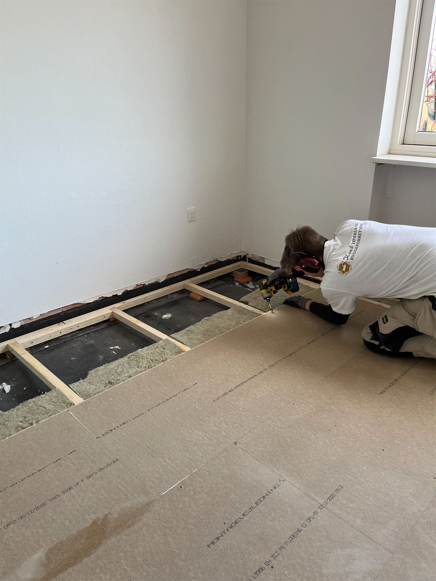 Tømrer i gang med at lægge nyt gulv på forsikringsopgave